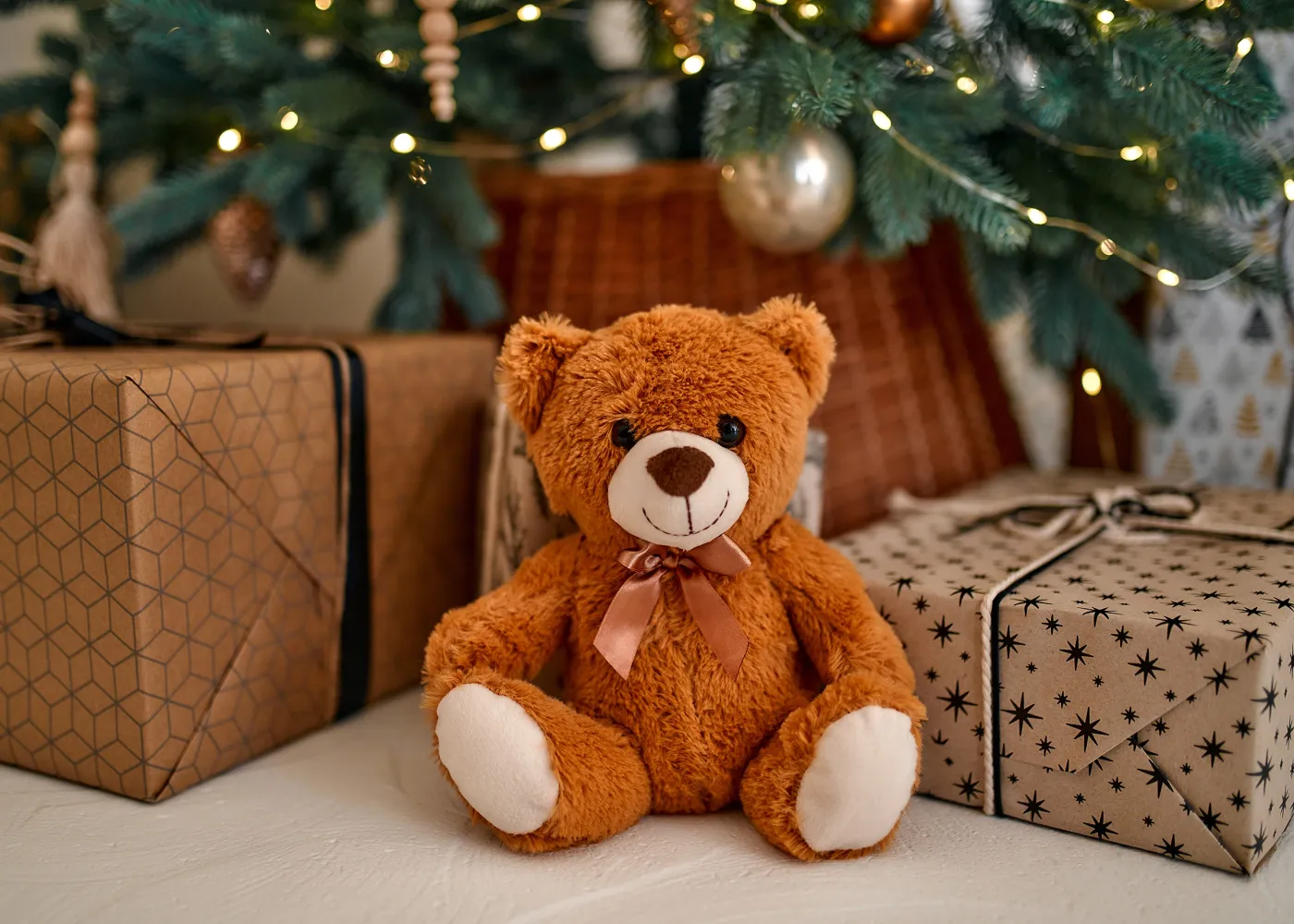 Teddy bear and gifts beneath a tree